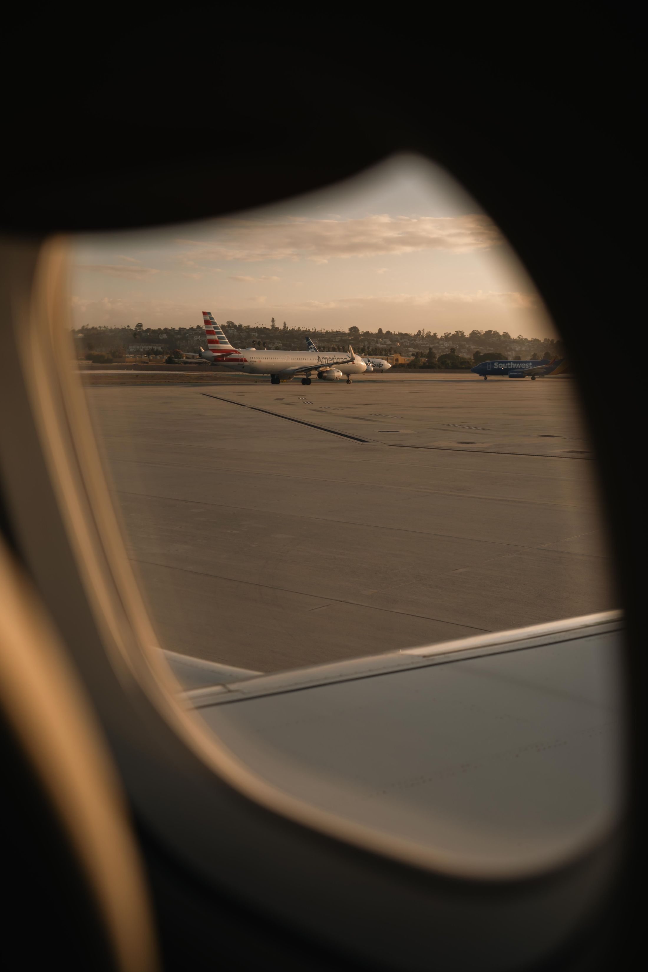 Aircraft and runway viewed through an aeroplane window at sunset